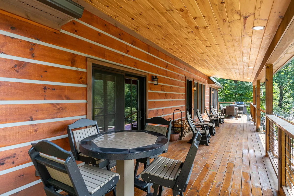 A cozy wooden porch furnished with outdoor seating and a table, overlooking natural surroundings. The porch provides a seamless transition between indoor comfort and the outdoors, making it an ideal spot for morning coffee or evening gatherings.