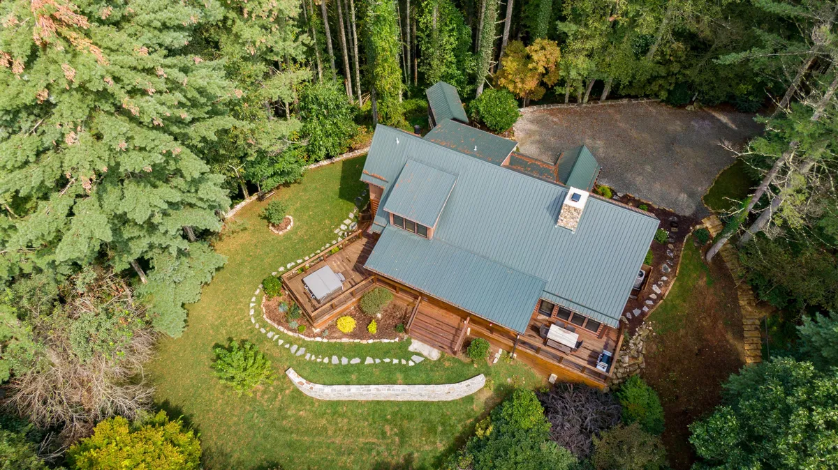 A view of the home’s exterior, framed by surrounding trees and landscaped gardens. The patio area invites guests to relax, enjoy nature, and start hikes or nature walks from their doorstep.