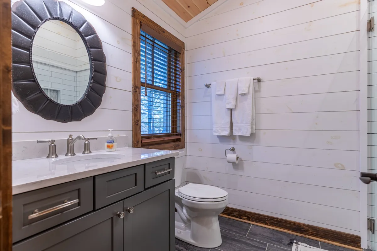 An inviting bathroom scene with a mirror above a vanity, a window streaming in the morning light, and freshly laundered towels neatly arranged, suggesting a space designed for relaxation and self-care.